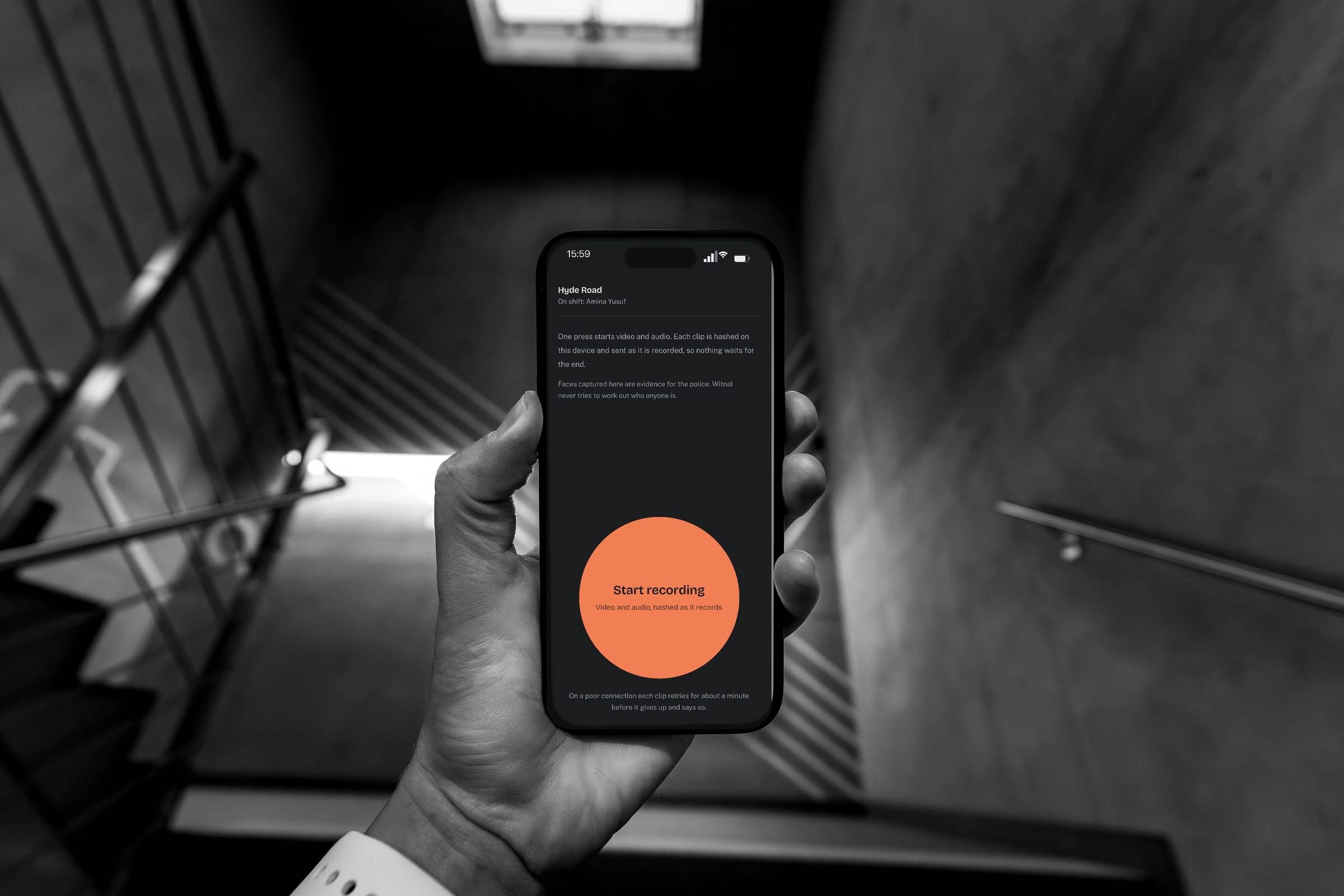 A hand holding a phone at chest height. On the screen, Witnal's capture page: one orange circle that reads Start recording.